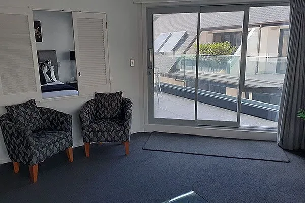 Living area with two patterned armchairs and sliding glass door to balcony.