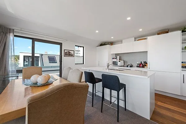 Open-plan kitchen and dining area with white cabinetry and city view.