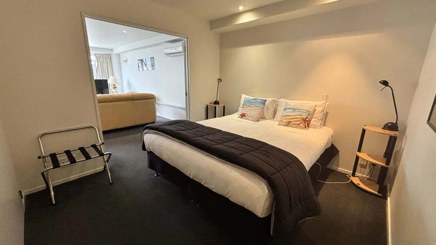 Bedroom with king bed, beach-themed pillows, and adjoining lounge area.