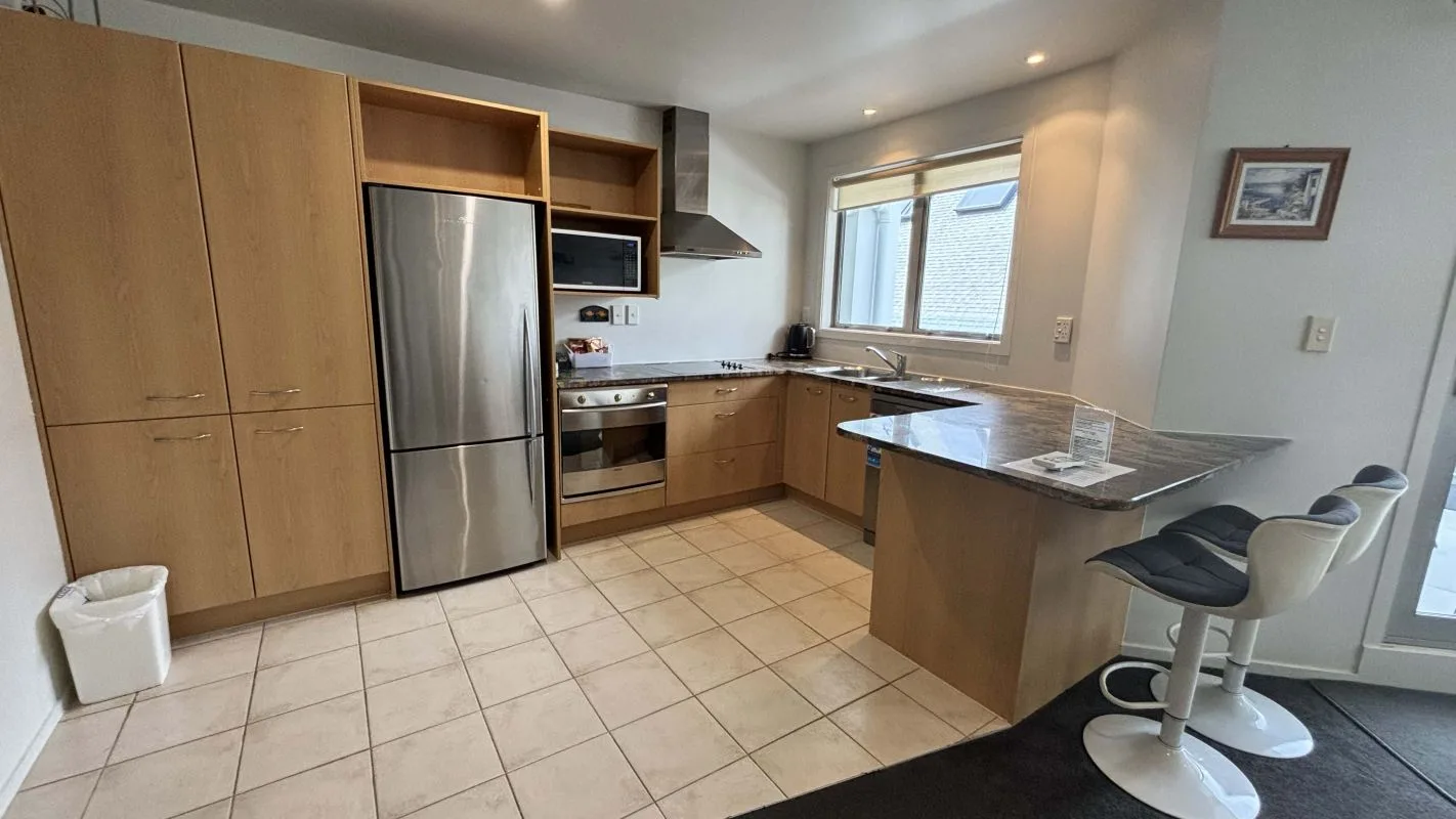 Kitchen with wood cabinetry, stainless steel appliances, and a breakfast bar with stools.