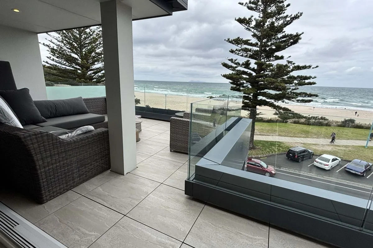 Balcony with wicker sofas overlooking the beach and ocean at Mount Maunganui.
