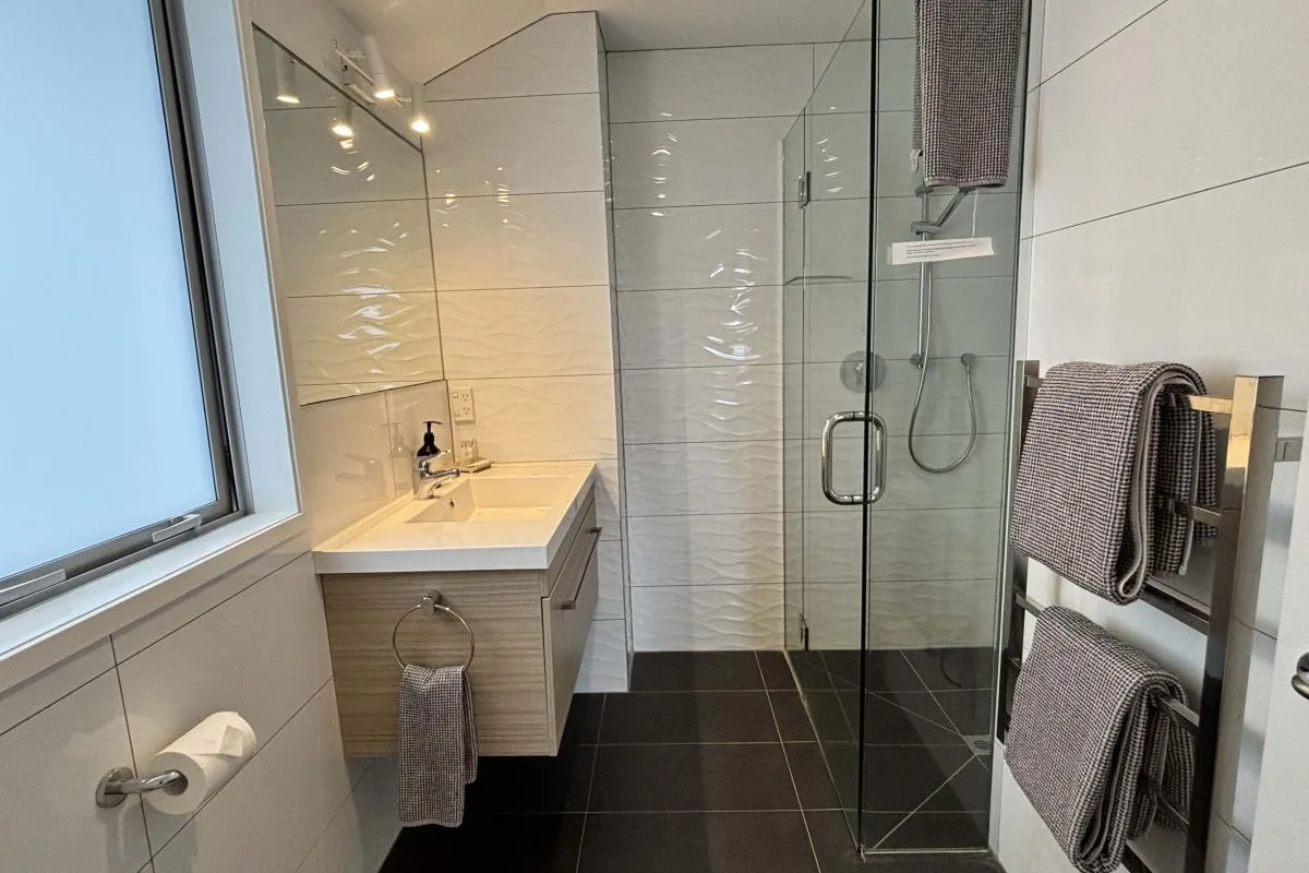 Bathroom with glass-enclosed shower, vanity sink, and heated towel racks.